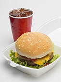 Cheeseburger in Verpackung, Cola im Plastikbecher