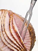 Roast ham, partly carved, with carving fork