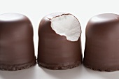 Three chocolate-coated marshmallow treats, one partly eaten