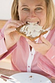 Woman biting into a slice of bread and butter