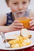Scrambled egg & toast, little boy in background drinking juice