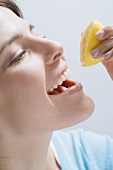 Young woman squeezing lemon juice into her mouth