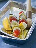 Vegetable kebabs in aluminium dish with oil and brush