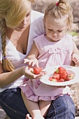 Mother and young daughter with a dish of strawberries