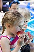 Kinder essen Wassermelone am Pool