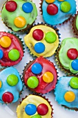 Chocolate cupcakes with coloured icing and chocolate beans