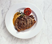 A grilled club steak with grilled tomato