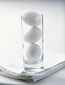 Three hens' eggs in a glass