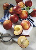 Whole and halved nectarines on chopping board with tea towel