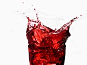 Cranberry juice splashing out of a glass