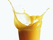 Mango juice splashing out of a glass