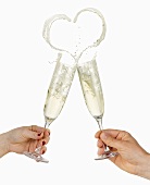 Clinking glasses of sparkling wine (with heart-shaped splash)
