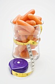 Baby carrots in glass with tape measure around it