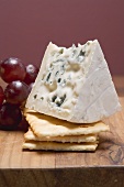 Piece of blue cheese with crackers and red grapes