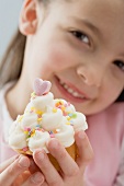 Little girl holding cupcake with cream and sugar confetti