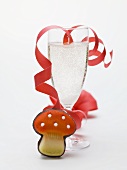 Glass of sparkling wine, paper streamer, marzipan fly agaric
