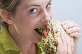 Woman biting into a sandwich with enjoyment