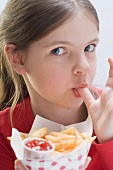 A girl eating chips, licking her thumb
