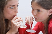 Girl and young woman drinking milkshakes
