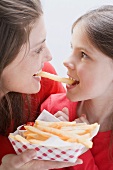 Young woman and girl eating the same chip
