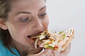 Young woman biting into a slice of vegetable pizza