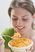 Young woman with pasta on spoon