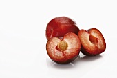 Red plums, one whole and one halved