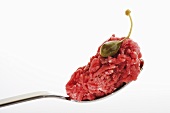 A spoonful of raw minced beef with giant caper