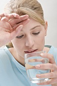 Woman with headache drinking glass of water