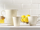 weiße Keramikkrüge, Zitronen und Honig