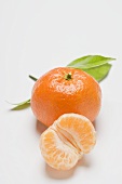 Clementine, unpeeled, peeled and leaves