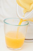 Pouring freshly squeezed orange juice into a glass
