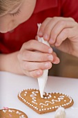 Kind verziert Keks mit Spritztüte