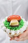 Hands holding cupcake with marzipan fly agaric