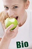 Woman eating organic green apple
