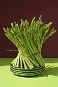 A bundle of green asparagus on stacked plates