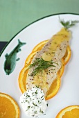 Pike fillet on orange slices with dill sauce