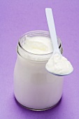 Yoghurt in jar and on plastic spoon