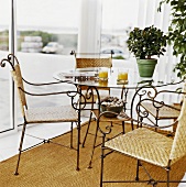 Orange juice, newspaper & azalea on glass table, four chairs