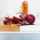 Dried chillies and red onions on chopping board