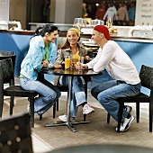 Zwei Frauen und ein Mann sitzen in einem Café
