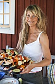 Blond woman carrying tray of food ready for barbecuing