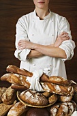 Baker with various rustic loaves of bread