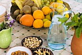 Fruit bowl, nuts and jug of water on table