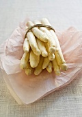 A bundle of white asparagus on paper