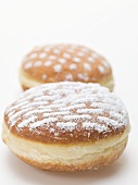 Two doughnuts dusted with icing sugar