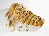Multigrain bread, partly sliced, with ears of wheat