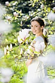 Young woman standing under flowering magnolia tree