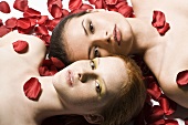 Zwei Frauen liegen auf Rosenblättern