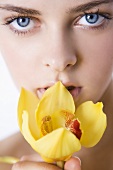 Junge Frau mit gelber Orchideenblüte